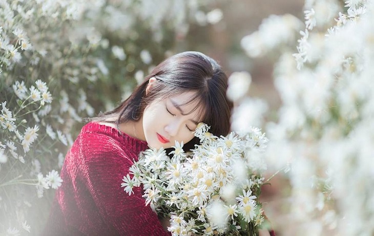 Một cô gái xinh đẹp mơ mộng mang theo hoa