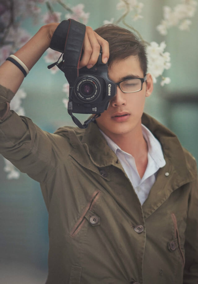 Hình ảnh một thanh niên đẹp trai che mặt với máy ảnh